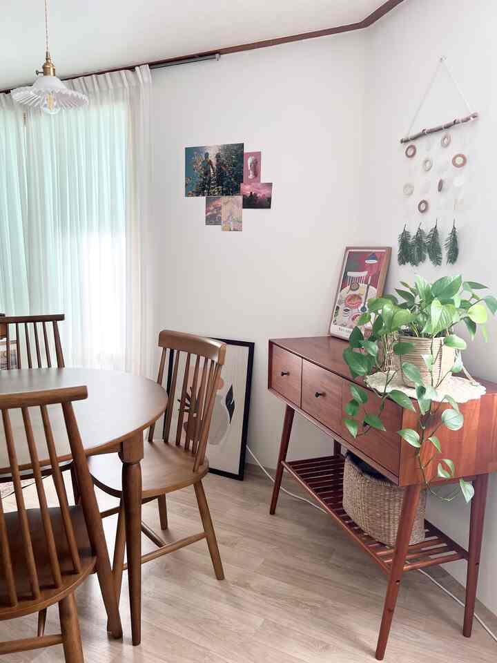 木目調と白を基調としたダイニング、木製のテーブルと椅子、植物や額縁が置かれた自然な雰囲気のインテリア