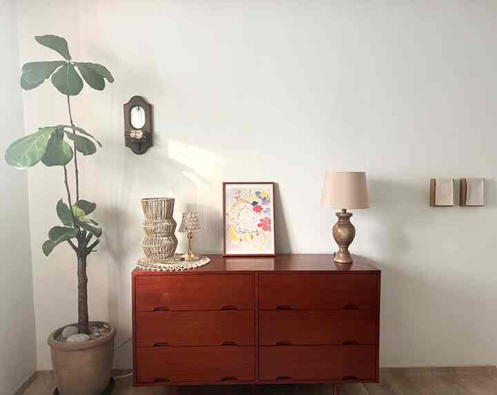 白い壁と茶色のチェストが配置された、自然でミニマルな雰囲気のリビングインテリア