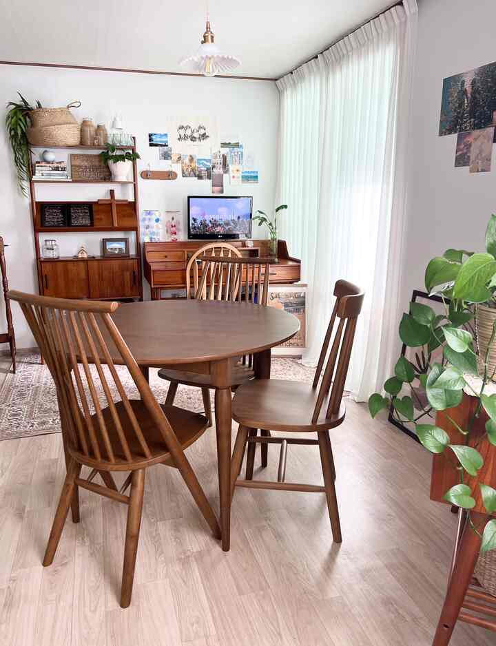 明るいホワイトトーンの壁とカーテン、ナチュラルなヴィンテージ風の木製ダイニングテーブルと椅子が配置された温かみのあるダイニングルーム