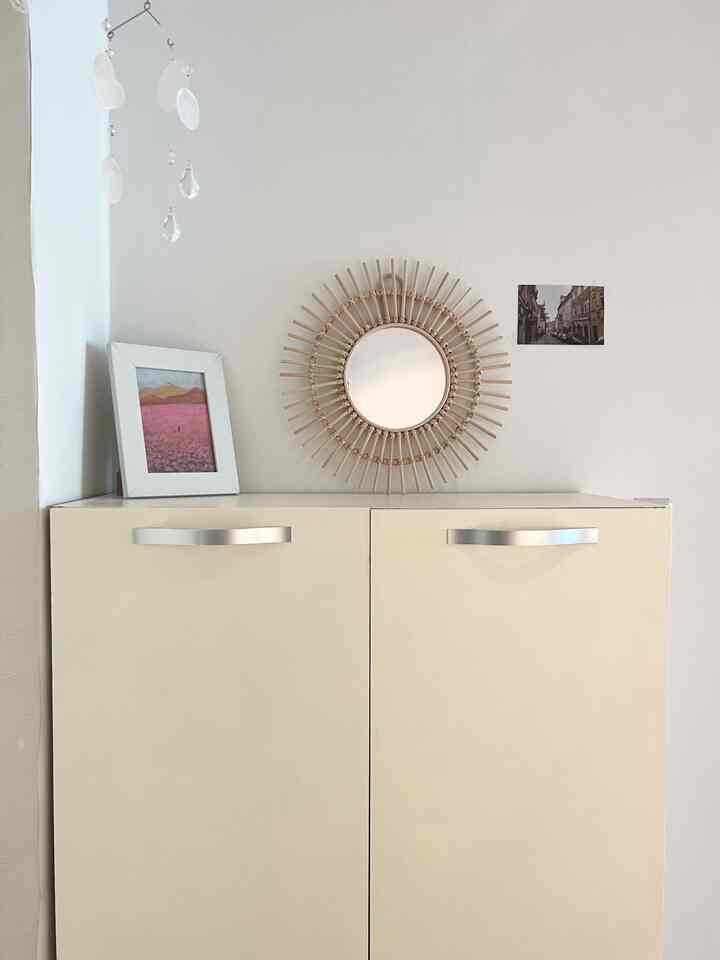 白とベージュの玄関、靴箱の上に丸い鏡と白い額縁が配置されたシンプルで落ち着いた雰囲気のインテリア