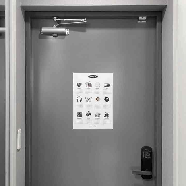 グレーの玄関ドアにカレンダーポスターが配置されたモダンでシンプルな印象的な空間