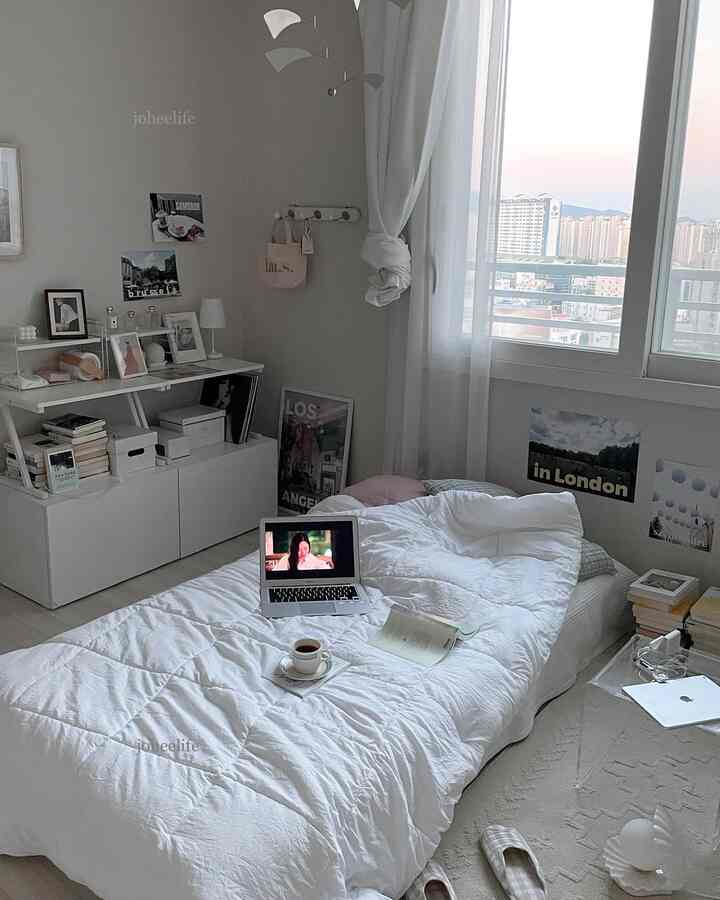 白とグレーのトーンの寝室、床に置かれたマットレスと窓際のカーテン、シンプルでミニマルな雰囲気のあるインテリア