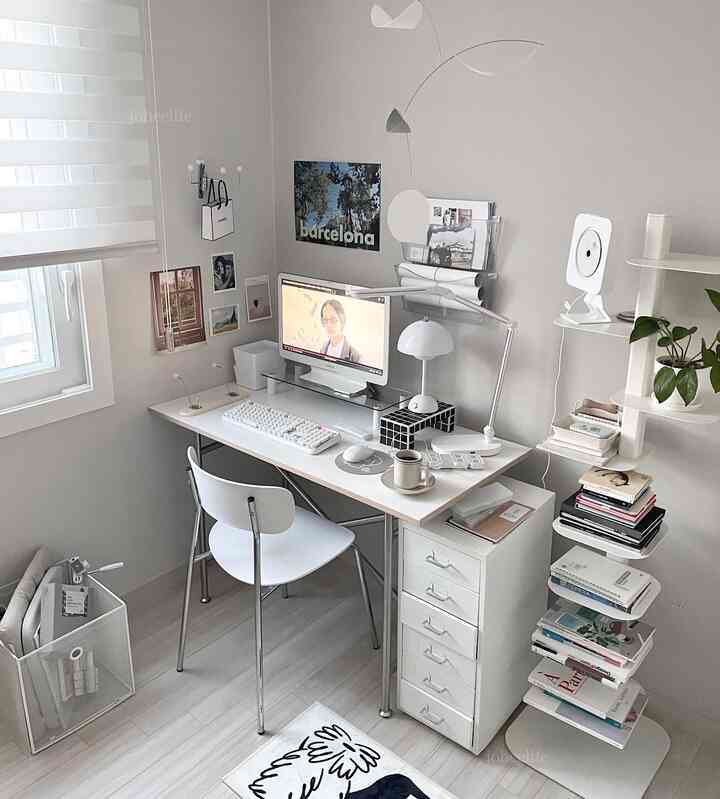ホワイトとグレーのトーンのコンパクトな書斎、整頓されたデスクと椅子、本棚に本が並ぶ落ち着いたホームオフィスのインテリア