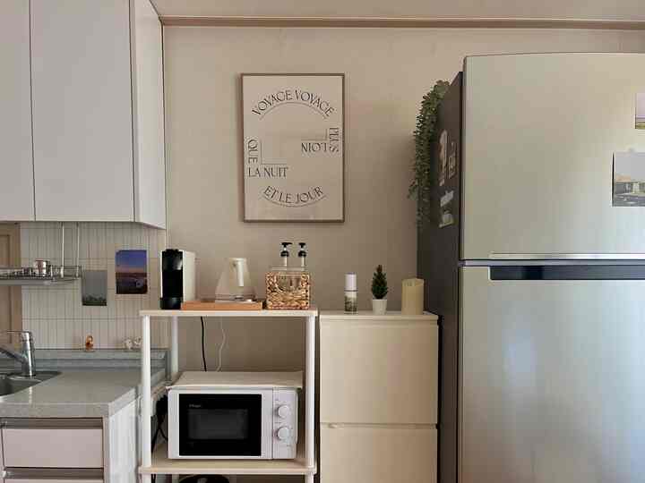 ナチュラルトーンのキッチン、コーヒーマシンと電気ケトルが置かれた棚、グレーの冷蔵庫が配された雰囲気のあるおうちカフェ空間