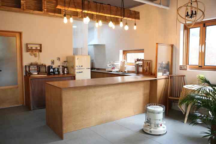 白い壁と木目調のシンクが調和するキッチン、ヴィンテージ冷蔵庫とペンダントライトが雰囲気ある空間を演出