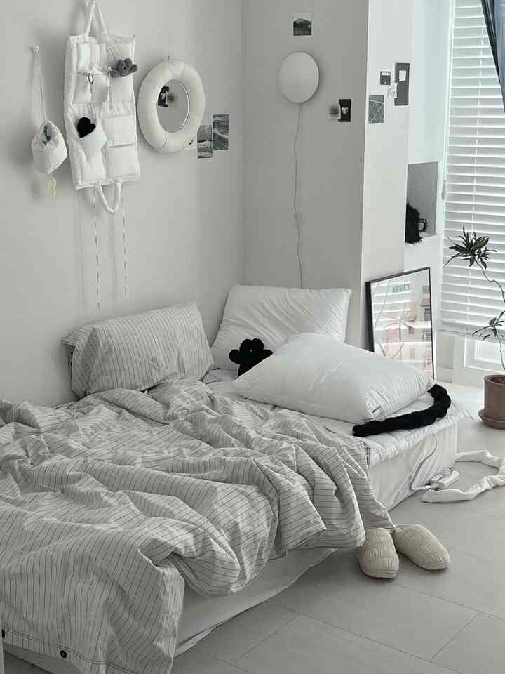 白を基調とした寝室、シンプルな寝具と小物が配置された落ち着いた雰囲気のインテリア