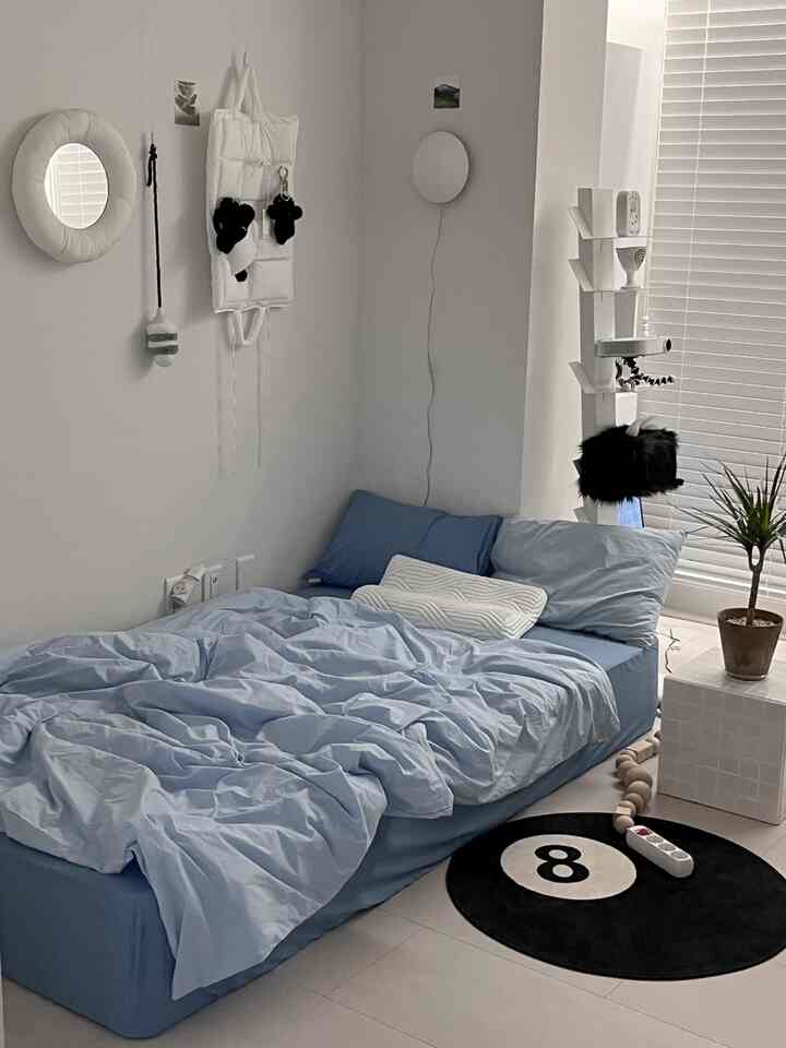 スカイブルーの寝具と白い壁、タイル製ナイトテーブルが配置されたシンプルでモダンな寝室