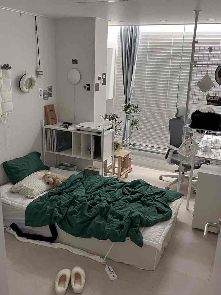 白と緑の色調の寝室、整ったベッドとデスク、ターンテーブルが配置された落ち着いたホームオフィス空間