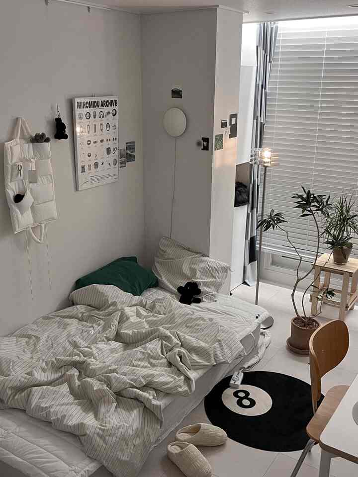 ベージュの色調の寝室、床にマットレスが置かれ、柱の壁灯とフロアランプが雰囲気のある空間を演出している