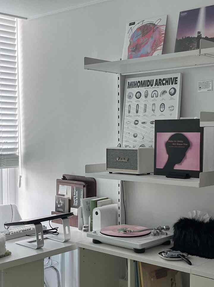 明るい白を基調としたホームオフィス、白いデスクと棚にレコードとスピーカーが配置されたモダンなインテリア