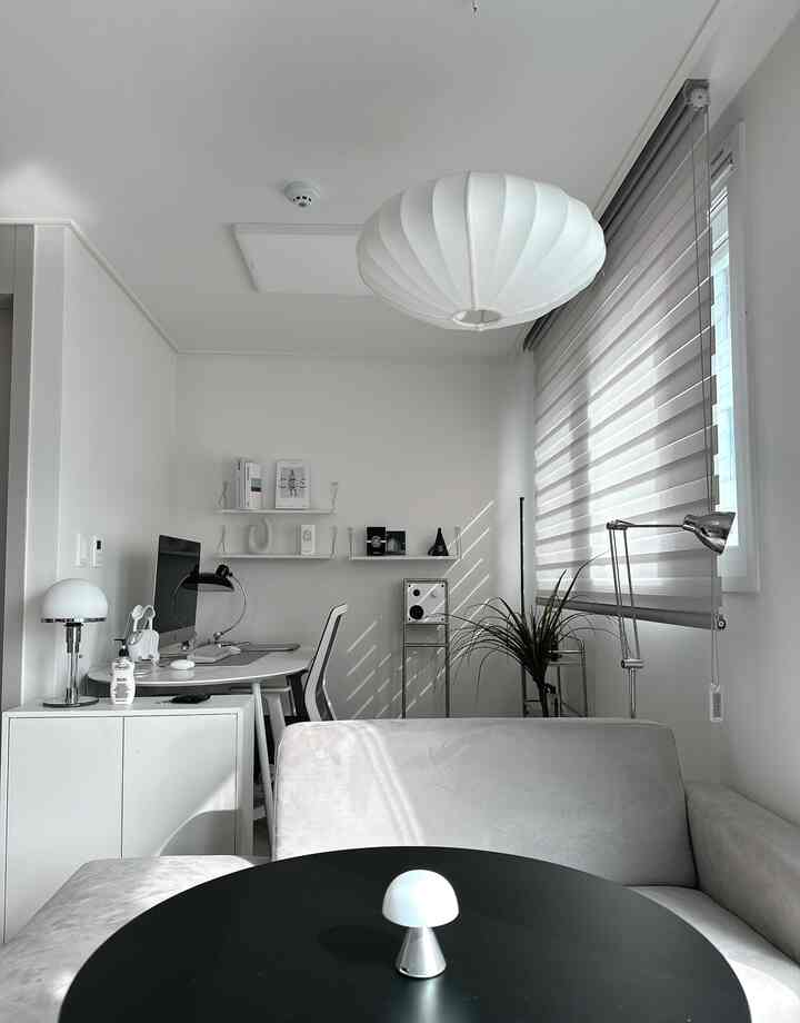 白を基調としたリビング兼ホームオフィス空間、黒い丸テーブルとモダンな家具が調和した印象的なインテリア