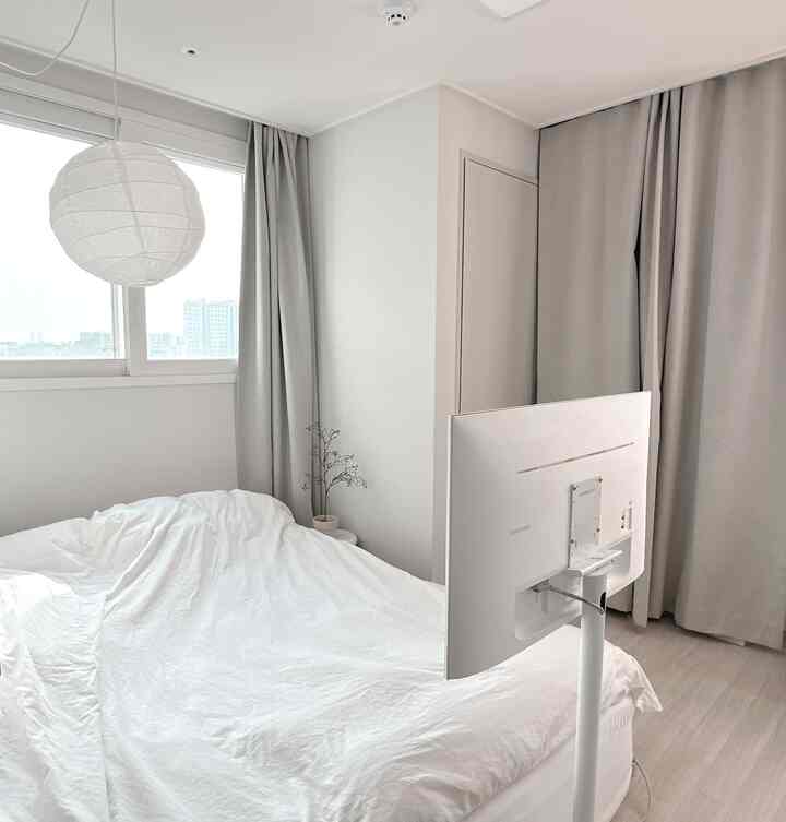 白を基調とした寝室、クイーンサイズのマットレスと白いカーテンが配置されたシンプルでモダンな雰囲気のある空間