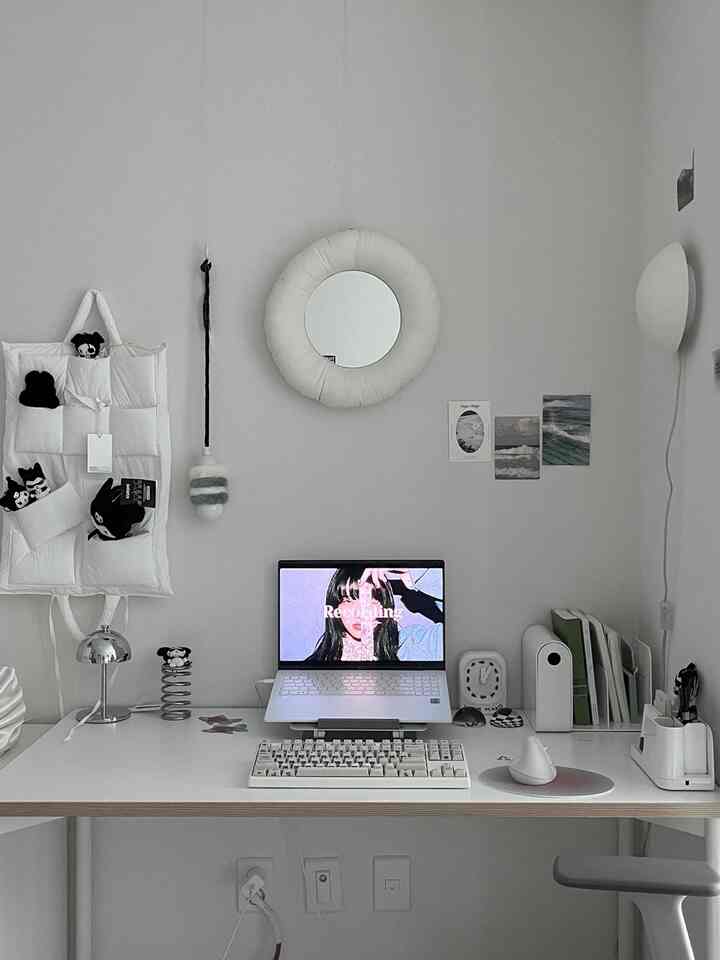 白を基調としたコンパクトなホームオフィス、中央に丸い鏡とノートパソコンが配置されたシンプルモダンな机のある雰囲気のあるインテリア