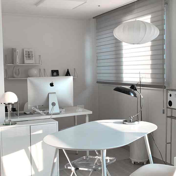 ホワイトトーンのホームオフィス空間、iMacデスクとダイニングテーブル、ペンダントライトが配置されたモダンで清潔感のあるインテリア