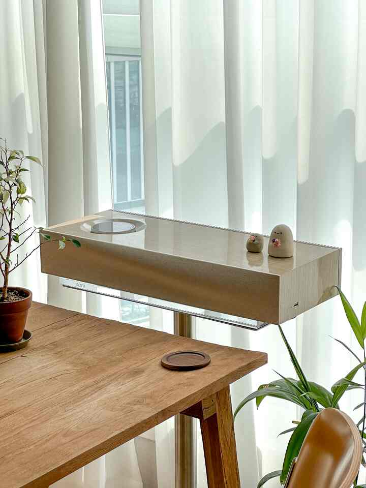 白いカーテンと木製のダイニングテーブル、植物が配置されたナチュラルトーンのキッチン空間