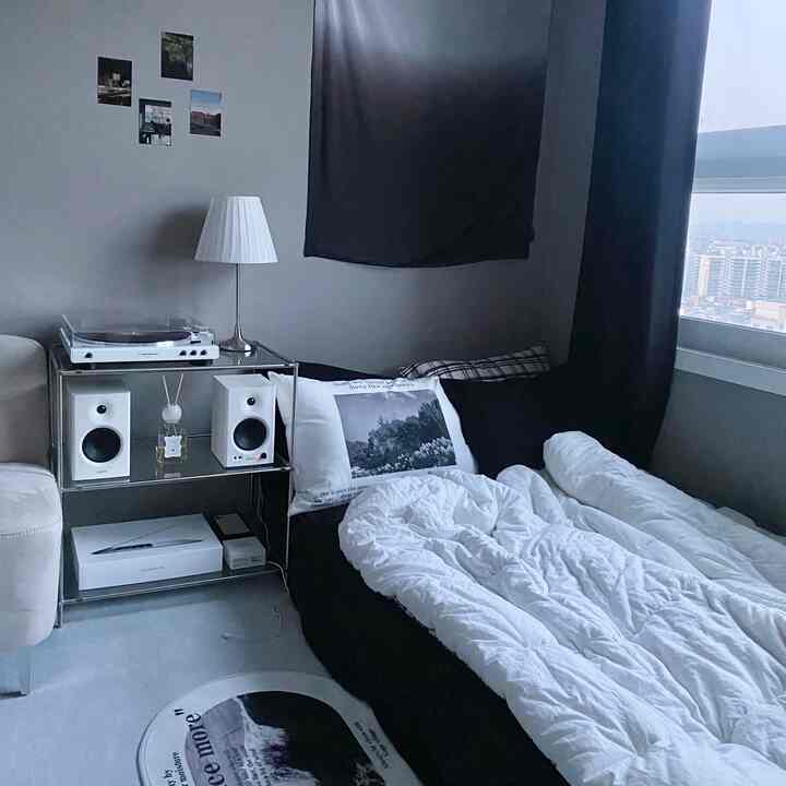 モノトーンのリビングルーム、ベッドとソファ、ターンテーブルとスピーカーが配置されたミニマルな空間