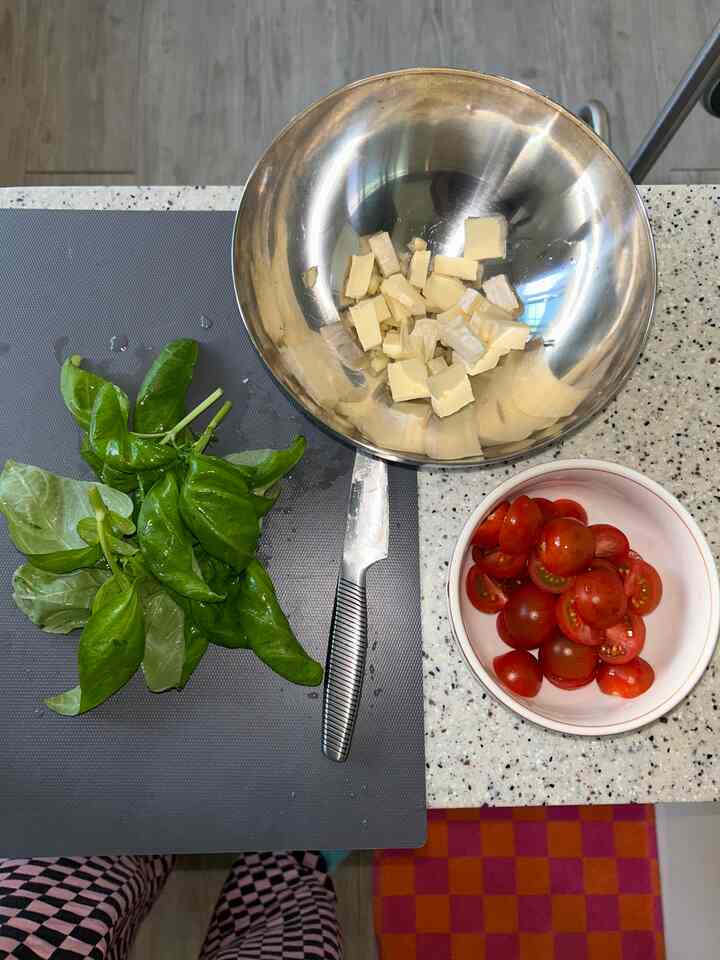 緑のバジルと赤いミニトマト、ステンレスボウルと包丁が置かれたキッチンカウンターの調理器具が配置された印象的な空間