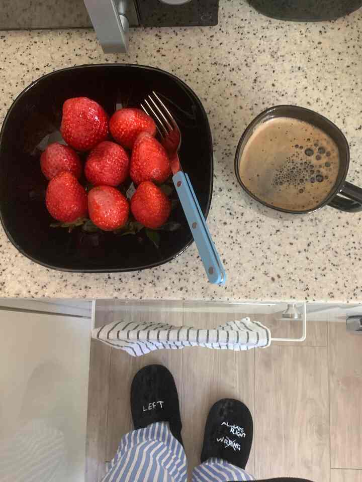 黒と白のトーンのキッチン、黒い皿にいちごがのり、隣にコーヒーマグとタオルが掛かっている清潔感のある朝の風景