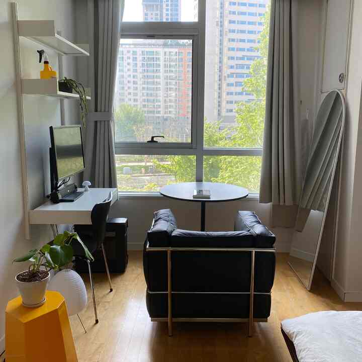 ホワイトとウッドトーンのコンパクトな一人暮らし用ホームオフィス、アーチ型の大きな鏡とシンプルな家具が配置されたミニマルなインテリア