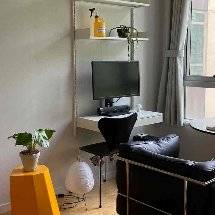 ホワイトとブラック、イエローが調和したコンパクトなワークスペース、机と椅子、ソファが配置されたモダンなインテリア