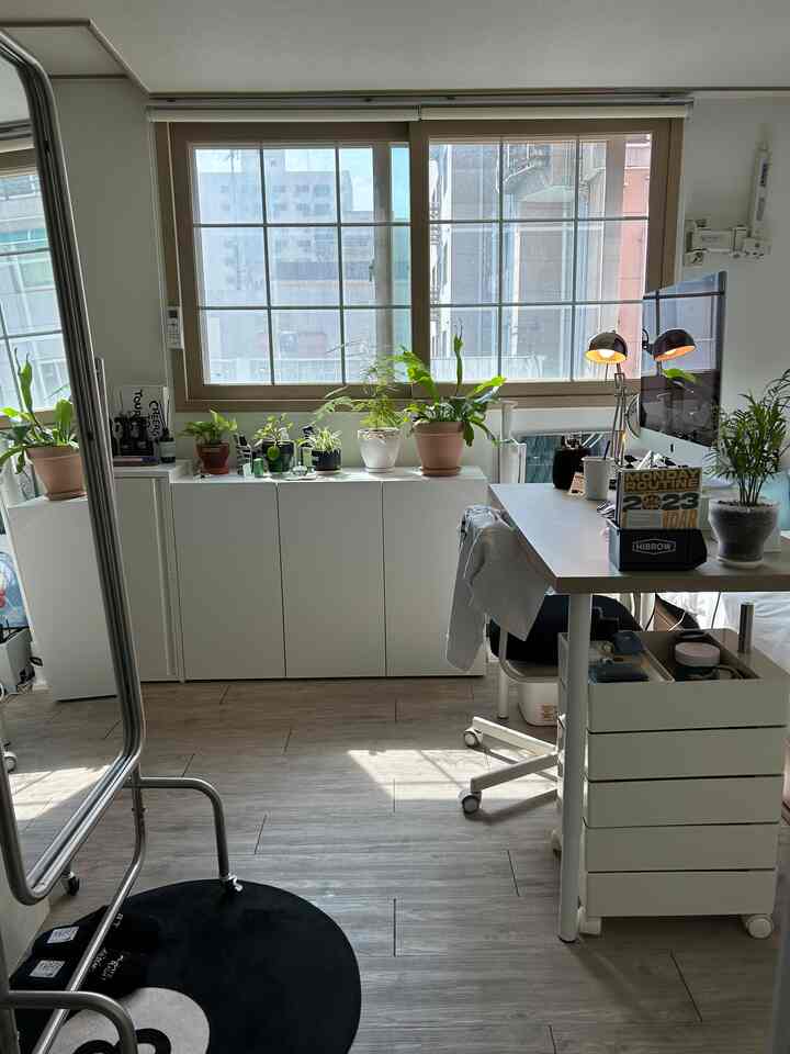 ホワイトとブラックのトーンのリビングルームの作業スペース、整然としたデスクと植物が配置されたモダンで明るい雰囲気のインテリア