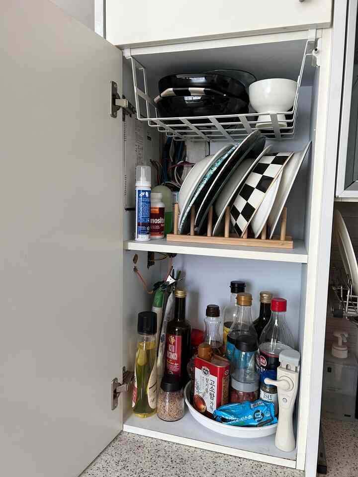 白を基調としたキッチン収納棚、皿と調味料の瓶が整頓された清潔なスペース