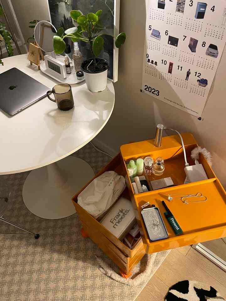 白とオレンジのトーンが特徴のワンルーム、丸テーブルとオレンジのトロリーが配置されたミッドセンチュリーモダンなコンパクトな空間