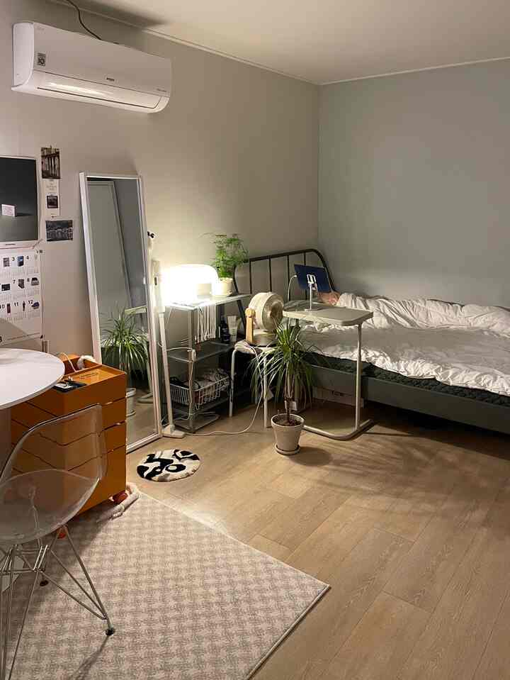 ホワイトとブラウンのトーンが特徴的な一人暮らし用の寝室兼ホームオフィス。ベッドとメタルシェルフ、全身鏡が配置されたすっきりとした空間