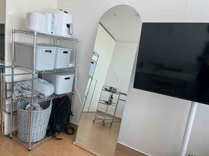 ホワイトとメタルの色調のキッチン兼収納スペース、大きな鏡と金属製の棚が配置された実用的な一人暮らし向けインテリア