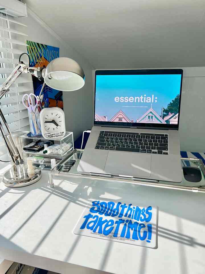 白とシルバーのトーンのホームオフィス、ステンレスのモニタースタンドとノートパソコンが整然と配置されたモダンなデスク