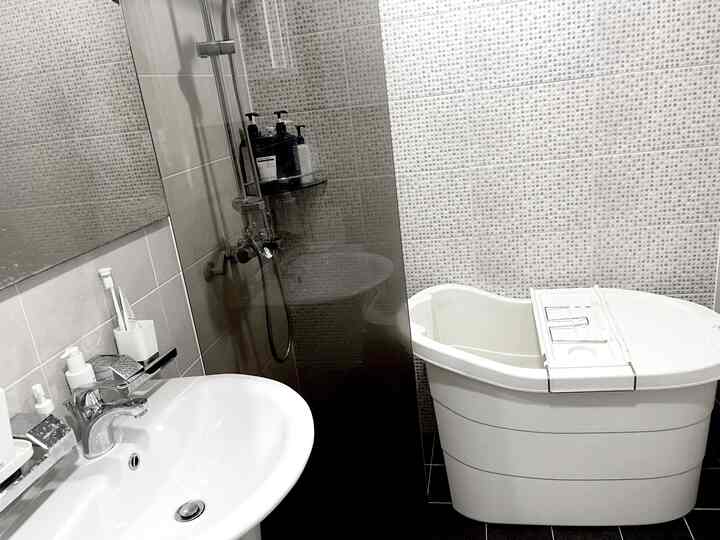 グレーと白を基調としたバスルーム、大型浴槽と洗面台が配置されたシンプルで清潔感のあるインテリア