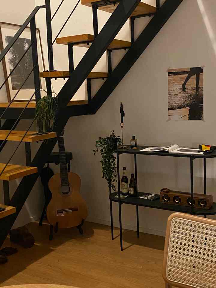 ウッドトーンとブラックが調和したナチュラルモダンな階段横の棚とギターが置かれた1階の印象的な空間