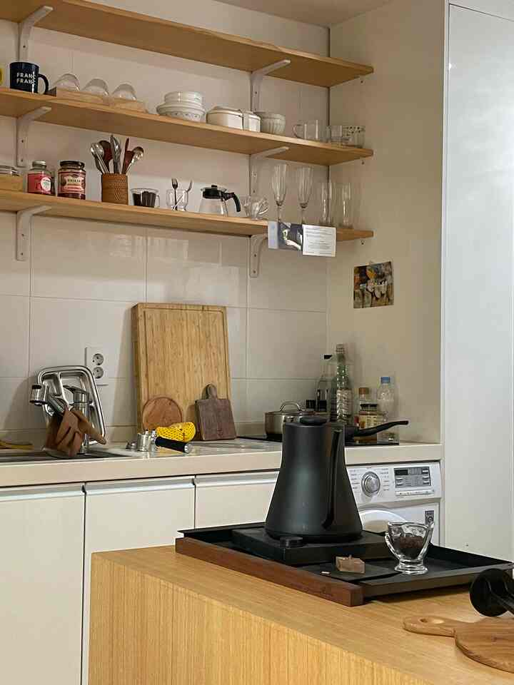 ナチュラルな木目調と白いタイルのキッチン、まな板やカトラリーが整然と並ぶ雰囲気のあるキッチン空間