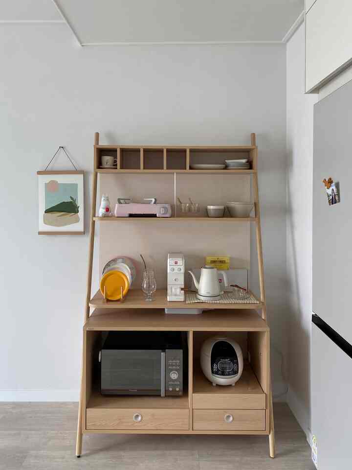 ナチュラルな木目調と白の色調のホームカフェ棚、電子レンジや炊飯器、コーヒーマシンが整った清潔なキッチンのインテリア