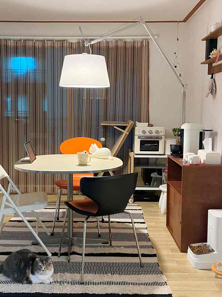 ナチュラルカラーのダイニングルーム、ホワイトのダイニングテーブルとカラフルなチェア、ペンダントライトが配置された雰囲気ある空間