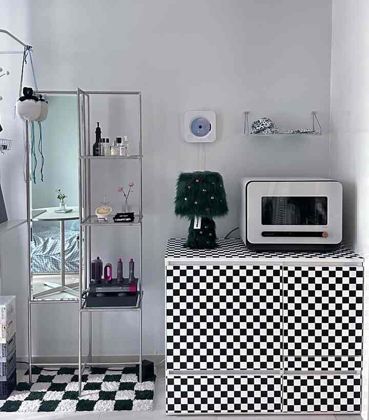 白い壁と黒白のチェッカーボードキャビネットが配置されたキッチン空間、シンプルでモダンなインテリア小物が飾られている