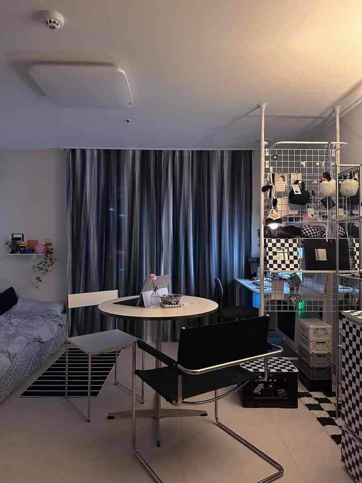 白と黒のモダンなワンルームバルコニー、丸テーブルとホームオフィスのある落ち着いたインテリア