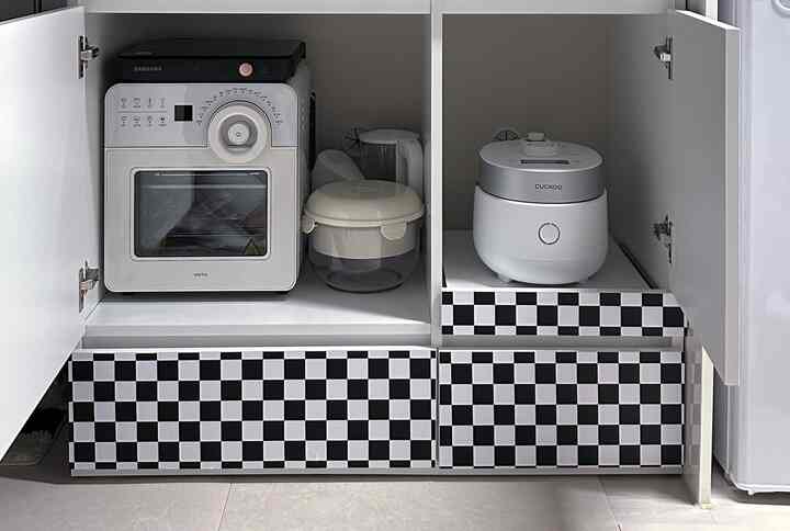 白を基調としたキッチンキャビネットの内部に、エアフライヤー、炊飯器、IH調理器が整然と配置された空間
