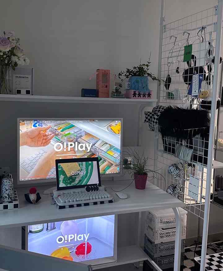 白色調のホームオフィス、棚付きの大きなデスクとモニター、整理された収納アイテムが配置された雰囲気のあるインテリア