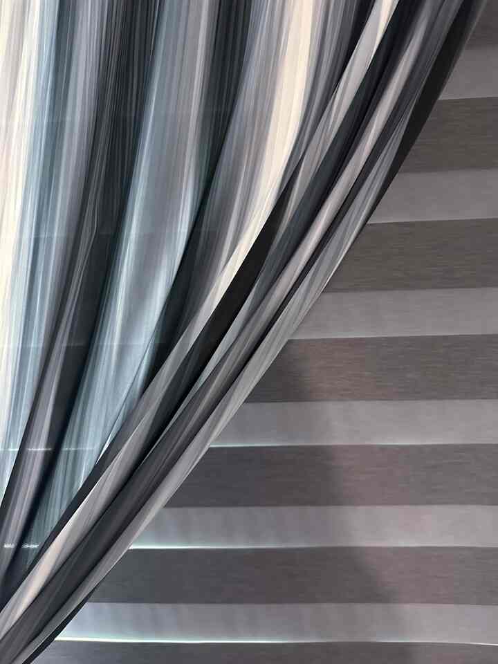 グレーとベージュのトーンの遮光ブラインドとシフォーンカーテンが配置された雰囲気のあるインテリア