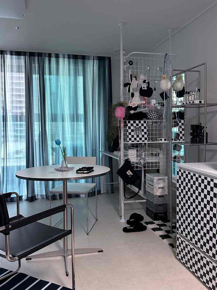 モノトーンのモダンなダイニングスペースで、白黒のパターン収納キャビネットと丸テーブル、黒のアームチェアが配置された落ち着いた空間