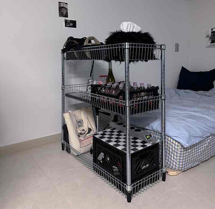 白い壁と黒いメタルシェルフが配置された一人暮らしの寝室、すっきりした収納アイデアが印象的なインテリア