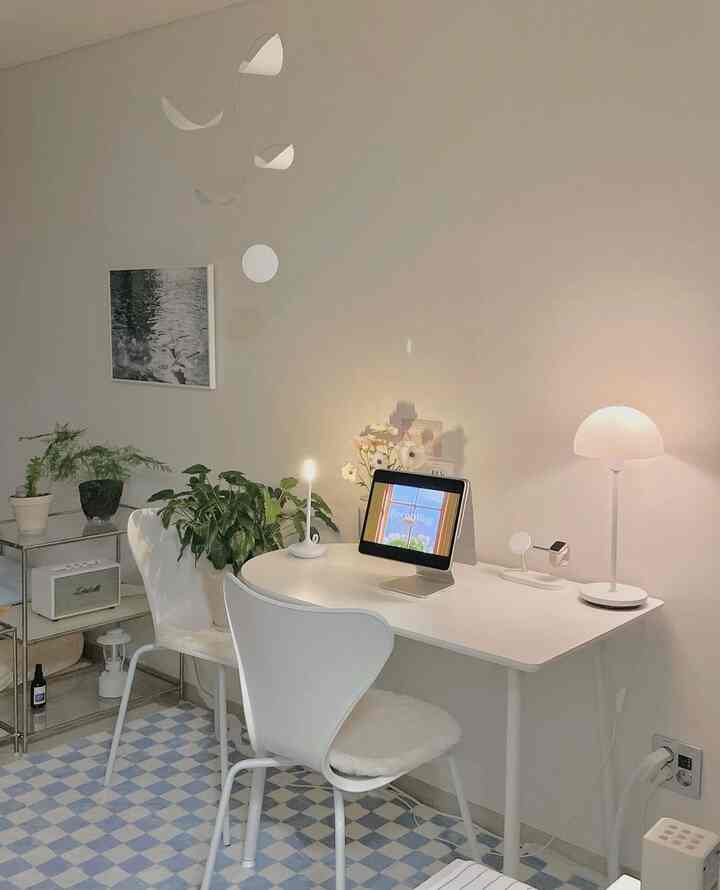 白い色調のホームオフィス空間、白いデスクと椅子、青チェックのラグ、多数の植物が配置された雰囲気のあるインテリア