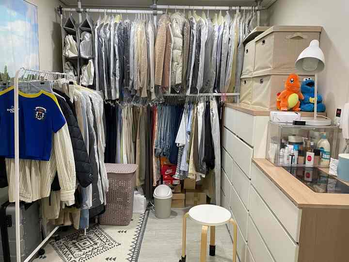 白と木目調のウォークインクローゼットとお手洗い、整理された洋服ラックとチェストが配置された実用的な空間