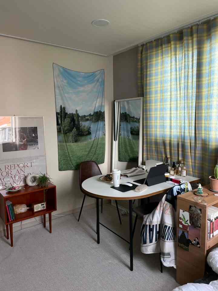 白と青のトーンのホームオフィス空間、楕円形の机と椅子、鏡、カーテンが配置された雰囲気のあるインテリア