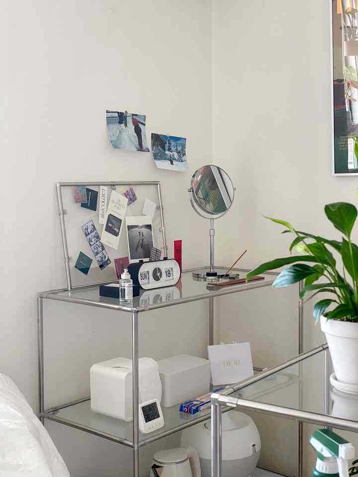 白い壁とクロームのメタル棚に写真、時計、鏡が配置されたミッドセンチュリーモダンの印象的な空間