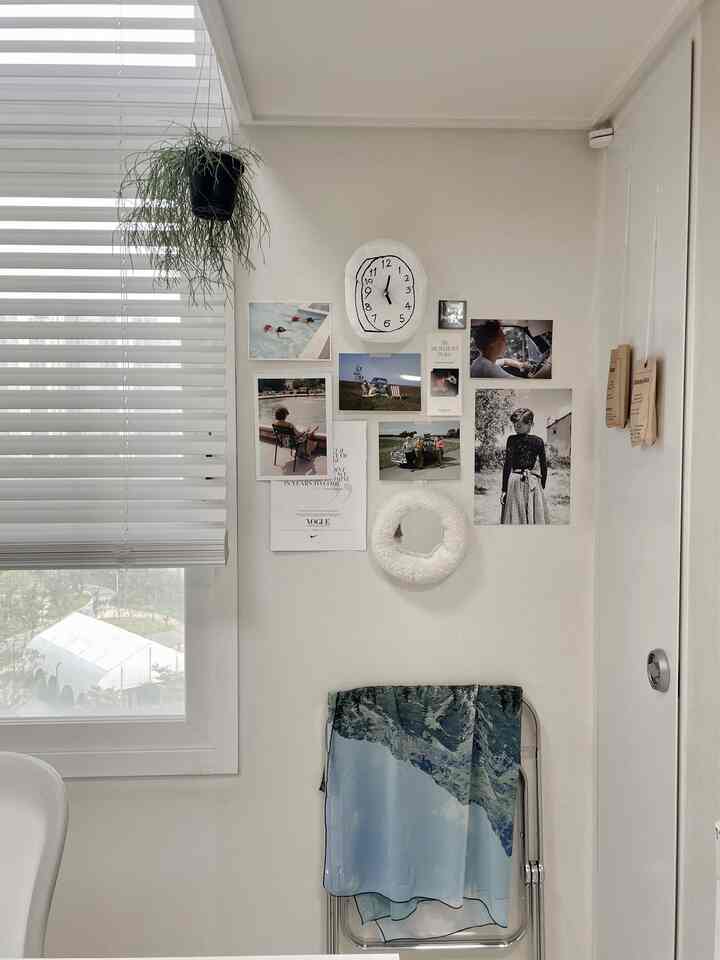 白を基調とした小さな空間、壁に写真のポスターが飾られ、透明な折りたたみ椅子に自然の風景の布がかけられた印象的なインテリア