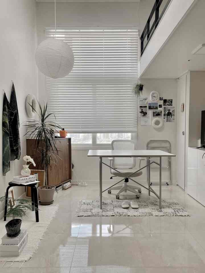 ホワイトとウッドトーンのリビングルームのホームオフィス、大きなデスクと収納キャビネットが配置されたシンプルな空間