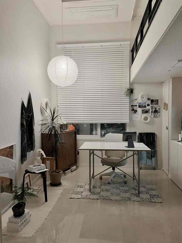 ホワイトとナチュラルな色調のロフトのホームオフィス、中央に机とペンダントライトが配されたミニマルな印象の空間