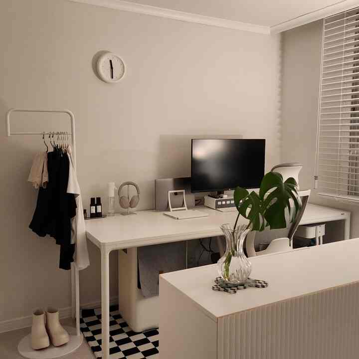ホワイトのホームオフィス、シンプルなデスクとチェアに植物が配された落ち着いた印象の空間